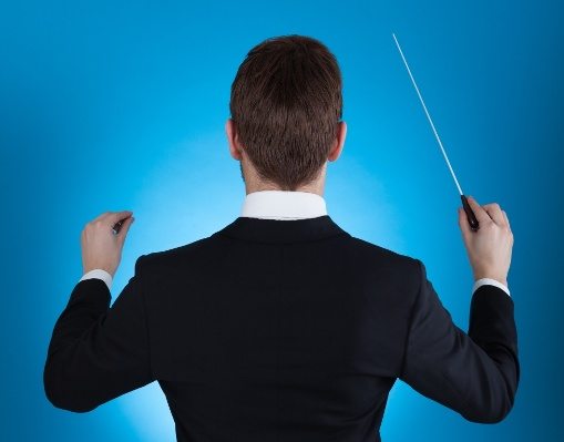 Rear view of orchestra conductor holding baton against blue background