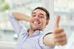 smiling man showing thumbs up at home or office